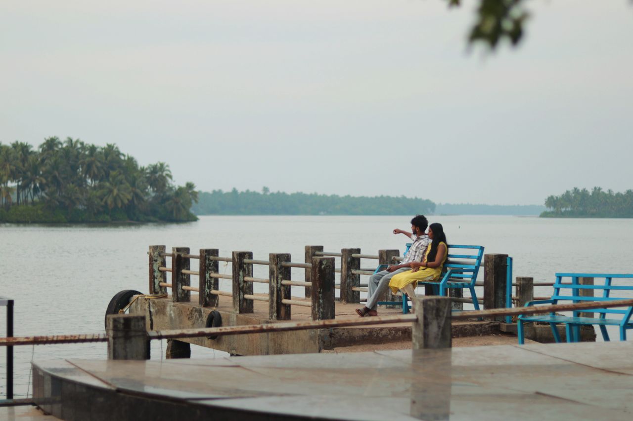 A couple quietly enjoying the scenic view from a pier by the water's edge in a tranquil setting.